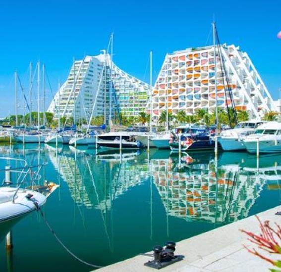 Le port de plaisance de La Grande Motte avec ses pyramides architecturales blanches emblématiques se reflétant dans l'eau.